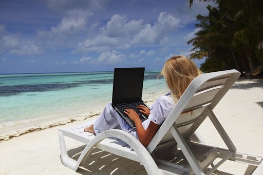 Девушка с ноутбуком на пляже работает